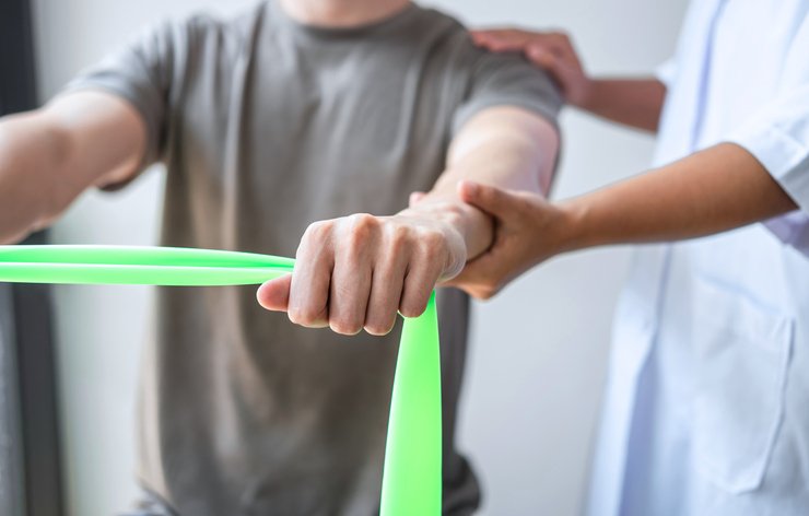 Female Physiotherapist working examining treating injured arm of athlete male patient, stretching and exercise, Doing the Rehabilitation therapy pain in clinic.